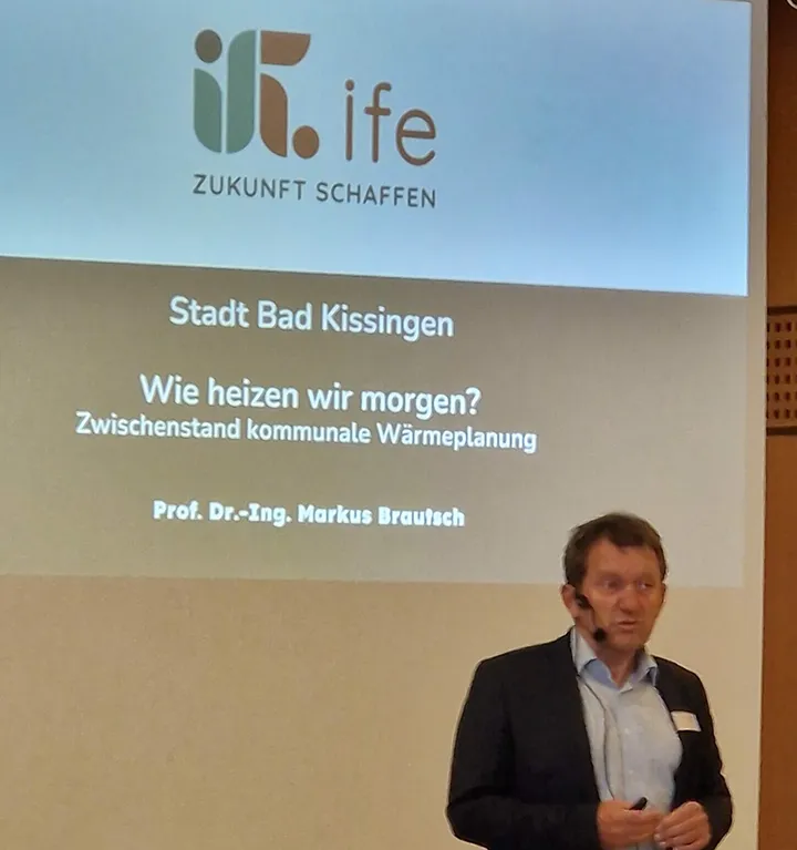 Vortrag von Prof. Dr.-Ing. Markus Brautsch zur kommunalen Wärmeplanung in Bad Kissingen mit dem Titel ‚Wie heizen wir morgen?‘ – Präsentationsfolie mit Logo des IfE im Hintergrund